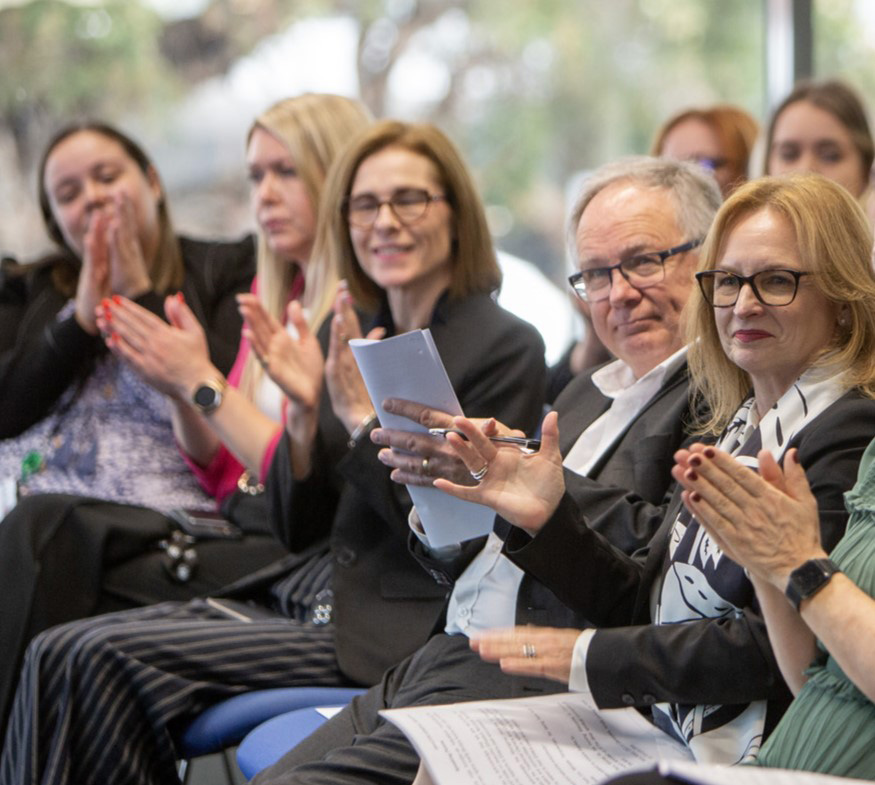 People clapping while seated at an event