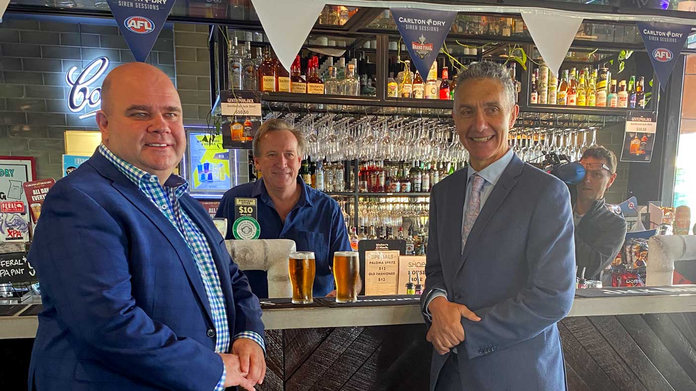 2 men at a bar with 2 beers served by bar owner