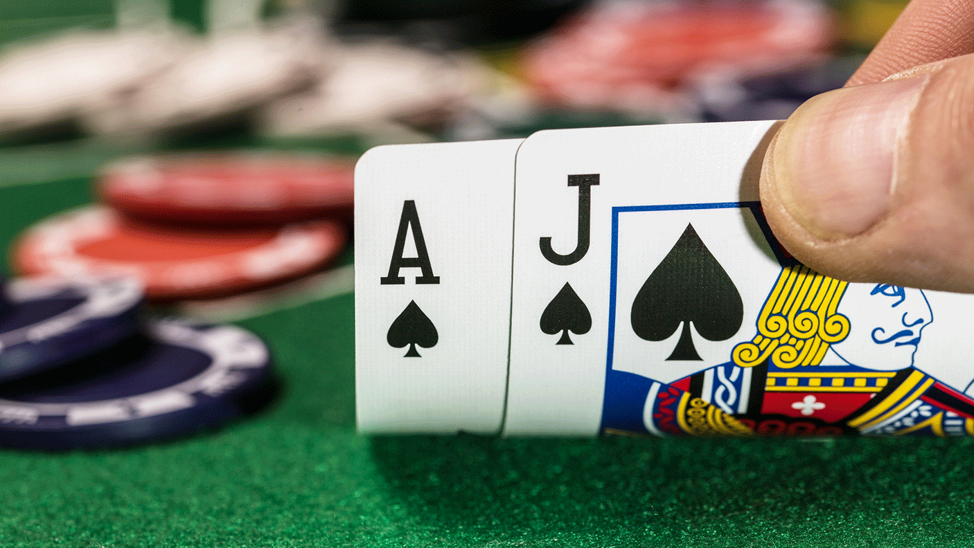 Close up of a poker hand with a jack and an ace of spade, and some gambling chips