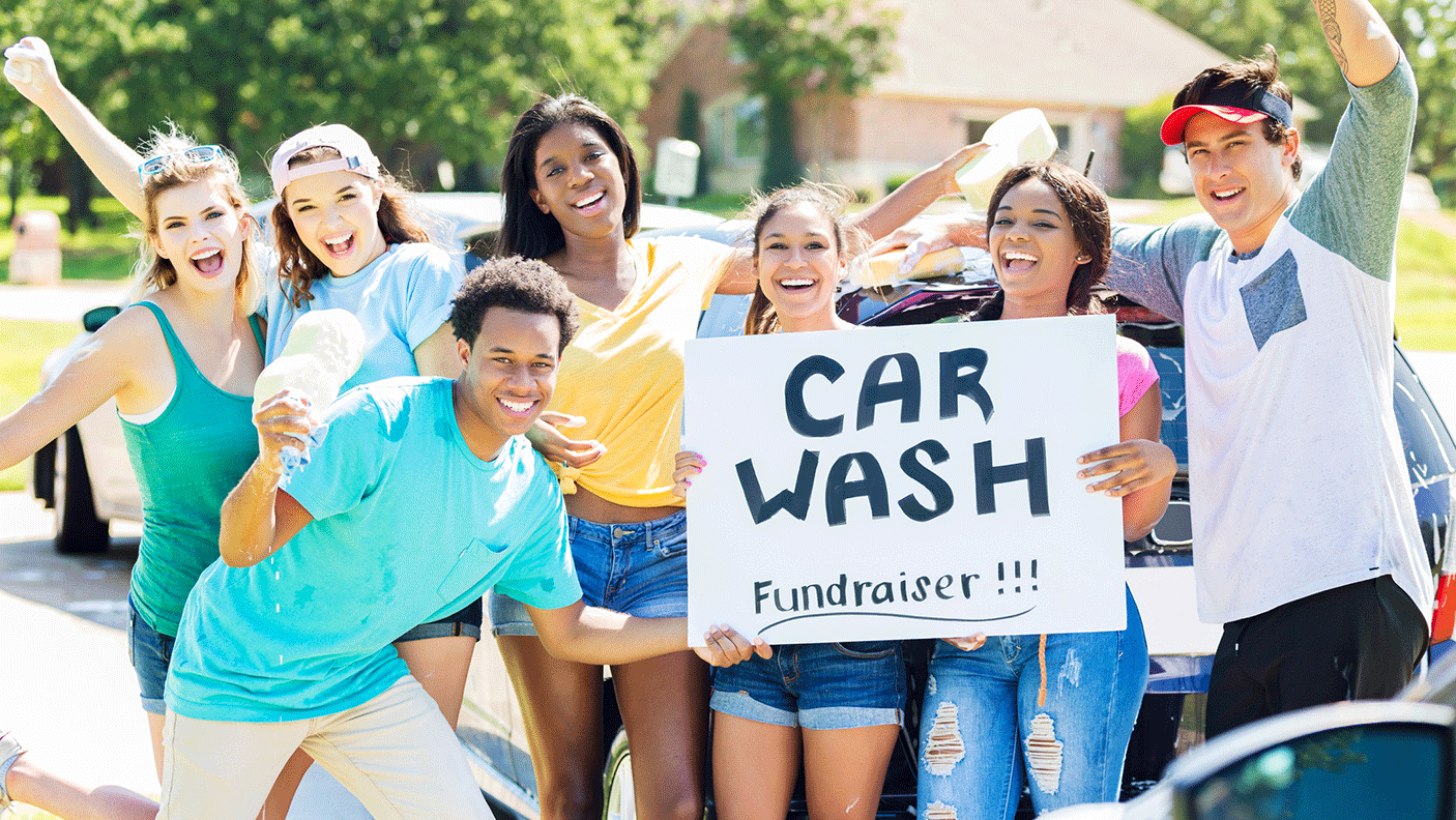 A group of young people hold up a sign for a charity car wash fundraiser