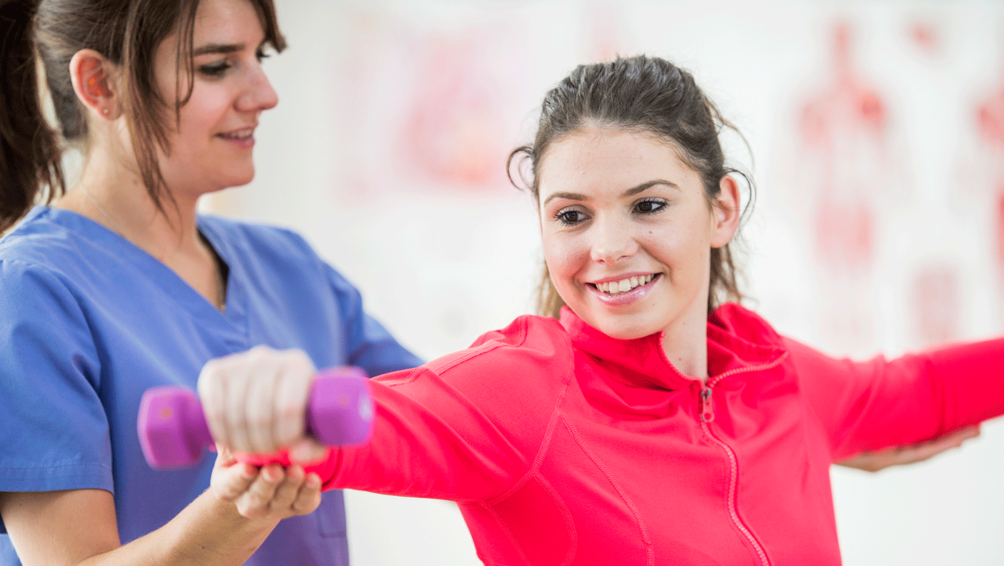 A physiotherapist assists a young person do some stretches