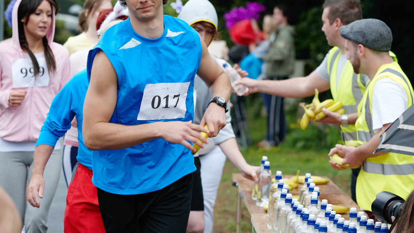 Volunteers hand out water and bananas to athletes running a race.